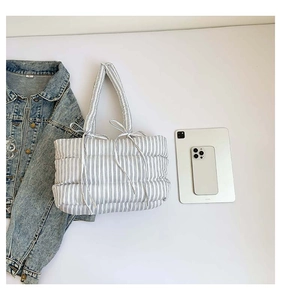 Détail du sac fourre-tout rayé matelassé avec poignée à nœud et texture rembourrée douce