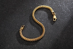 Bracelet chaîne épi en acier inoxydable doré poli avec fermoir mousqueton sur fond noir