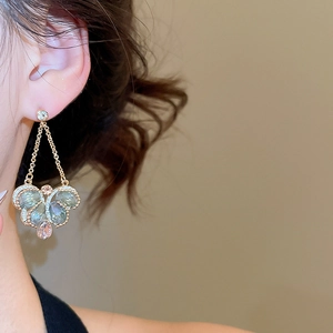 Close-up of vintage crystal butterfly drop earrings with pink and green stones on model