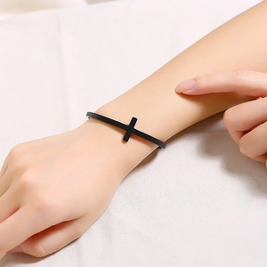 Minimalist black stainless steel cross cuff bracelet shown on a person's wrist