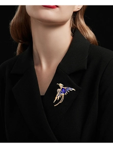 Detail of phoenix brooch with blue crystals pinned on a black blazer lapel
