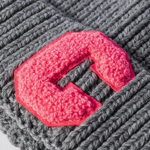 Grey knit beanie with pink C letter patch showing thick texture and warm ear protection