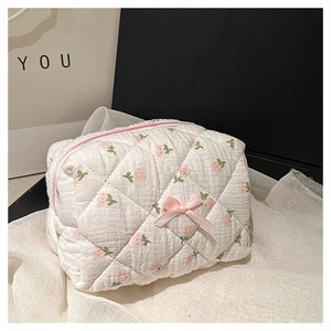 Detail of white quilted makeup bag with pink rose patterns and cute bow decoration
