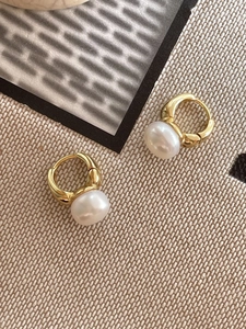 Detailed top view of 925 silver pearl hoop earrings on beige textured background