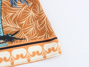Detailed close-up of brown coconut tree print dress featuring asymmetric hem and fine stitching