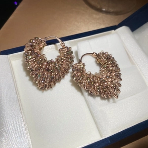 Close-up of champagne crystal beaded heart hoop earrings with rose gold metal finish