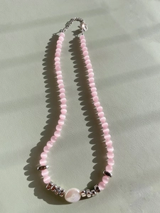 Detail of pink cat-eye bead necklace with pearl pendant and silver lobster clasp