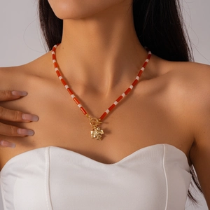Detail of red and white beaded necklace with golden maple leaf pendant and OT clasp