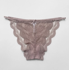 Detailansicht aus grau-rosa floraler Spitze mit kleiner Schleife und gewellten Kanten