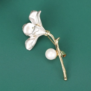 Detail of trumpet flower brooch featuring silver petals, golden stem, and pearl accent