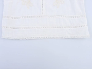 Detailed view of delicate hollow lace trim and floral embroidery on white cotton fabric