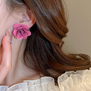 Gros plan d'une boucle d'oreille fleurie rose foncé portée par un mannequin