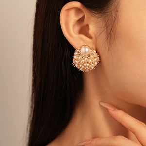Close-up of vintage pearl stud earring with rhinestones on model's ear in warm light