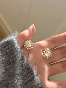 Close-up of elegant gold plated flower earrings with white pearls and sparkling zircons