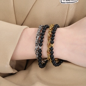 Close-up of four-piece stackable bracelet set with matte black beads and metal chains