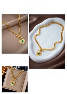 Detail of gold heart pendant with green gemstone and OT toggle clasp on Cuban chain