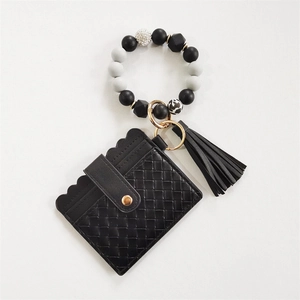 Detail view of black woven PU leather wallet with beaded bracelet and gold keyring tassel