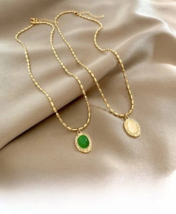 Detail of vintage gold bead necklaces with green gemstone and opal oval pendants