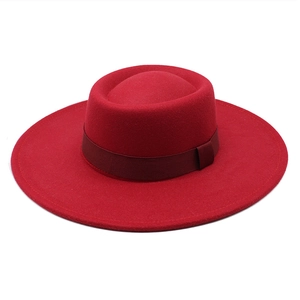 Top view of bright red wool felt boater hat featuring a wide brim and ribbed ribbon band