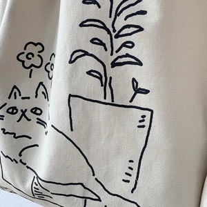 Close-up of cream canvas tote bag showing textured fabric and hand-drawn cat print