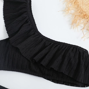 Macro detail of black ruffle bikini top featuring textured eyelet fabric and wavy edges
