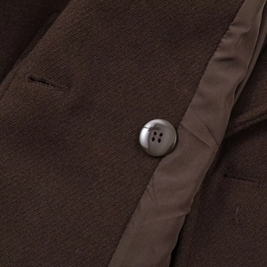 Detailed close-up of dark brown twill fabric with matching resin button on stylish coat