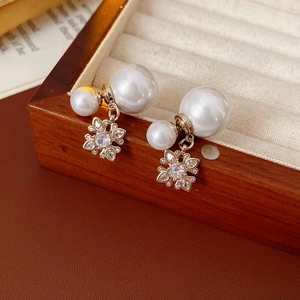 Detailed macro shot of floral pearl earrings with zircon inlay in a wooden box