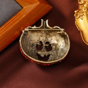 Antique bronze pumpkin brooch with red rhinestones on a dark textured background
