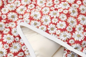 Detail van de madeliefjesquilting en stiksels op de rode gewatteerde katoenen jas