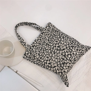 Detailed close-up of a black canvas tote bag featuring a white floral pattern and minimal design