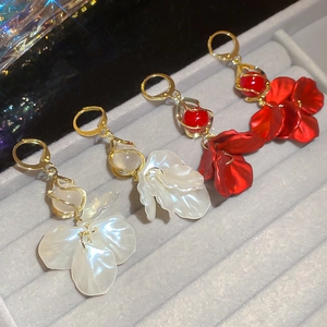 Detail view of pearl petal tassel earrings in white and red on jewelry tray