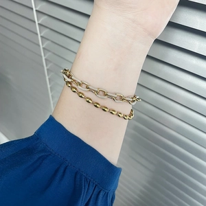 Gros plan détaillé de bracelets à double couche avec billes dorées et maillons de chaîne