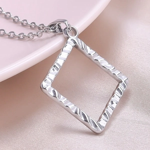 Makroaufnahme quadratischer Silberanhänger mit unregelmäßiger Wellentextur an Metallkette