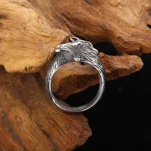 Macro shot of vintage silver double wolf head steel ring on a rustic wooden base
