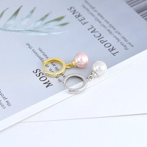 Detailed view of elegant drop pearl earrings in gold and silver finishes on a leaf card