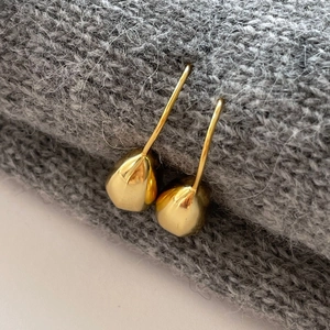 Detailed close-up of golden irregular water drop earrings with polished mirror finish