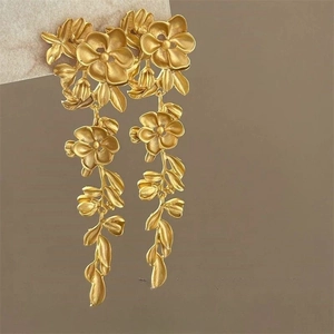 Detailed close-up of golden matte flower petal drop earrings with elegant long tassels
