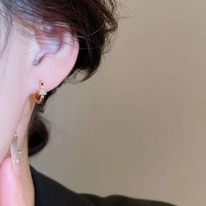 Close-up of 18k gold plated hoop earring with tiny zircons worn by a model