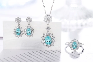 Close-up of a silver jewelry set featuring light blue oval gemstones and halo diamonds