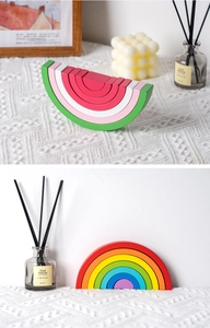 Detail of wooden rainbow and watermelon arch blocks on a soft white knit surface