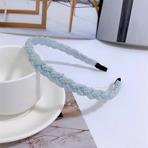 Detail of light blue braided headband with tiny beads on a white tabletop setting