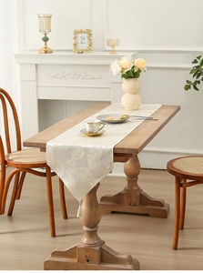 Detail of off-white jacquard table runner with embroidered leaves and tassels