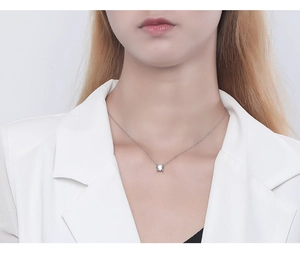 Close-up of a delicate S925 silver necklace with a sparkling round zircon pendant on a model