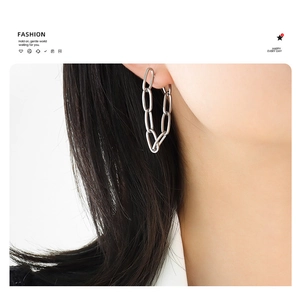 Close-up of trendy silver double chain tassel earrings worn by a model in a fashion style