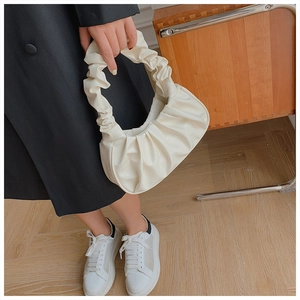 Detail view of beige ruched cloud bag with soft pleated texture and shoulder strap