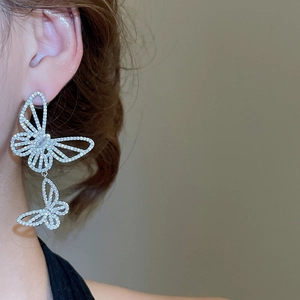 Close-up of sparkling zircon butterfly earrings with silver needle on a female model