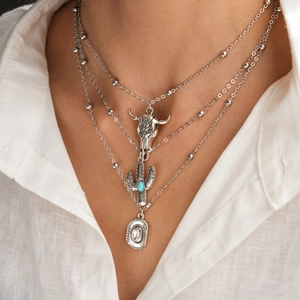 Detail of layered silver necklaces with bull skull, cactus, and cowboy hat pendants