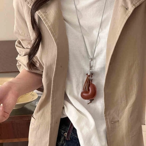 Detail of a brown leather croissant pendant with fringe on a silver long chain necklace