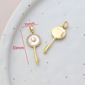 Macro detail of 14k gold-filled key pendant with white shell and measurements 11x33mm