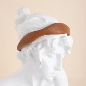 Detail of wide padded brown leather headband showing grainy texture and soft matte finish